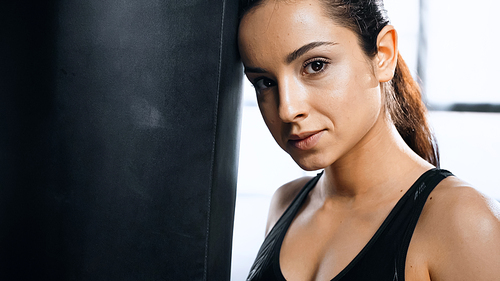 exhausted woman leaning on punching bag in gym