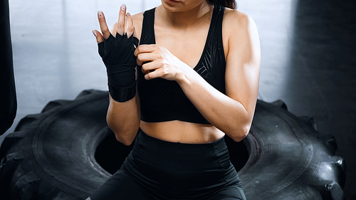 cropped view of young sportswoman putting on hands boxing bandages