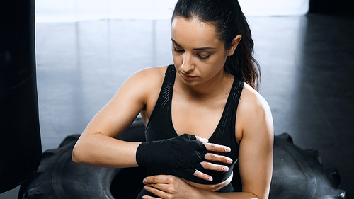 young brunette sportswoman putting on hands boxing bandages
