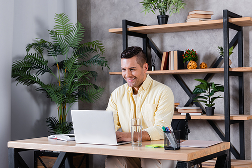 disabled man smiling while typing on laptop at home