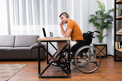 disabled man in headset working near laptop at home
