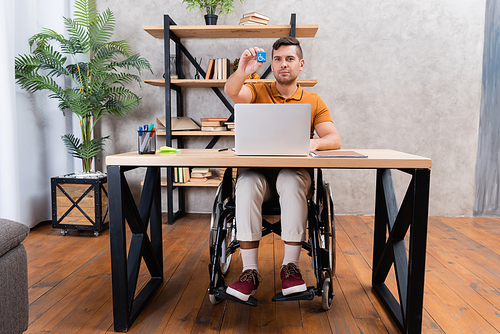 handicapped man showing cube with disability symbol while working in home office