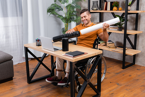 disabled architect putting paper into drawing tube while working in home office