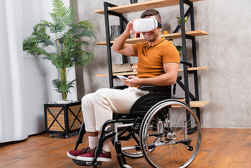 cheerful disabled man touching vr headset while gaming at home
