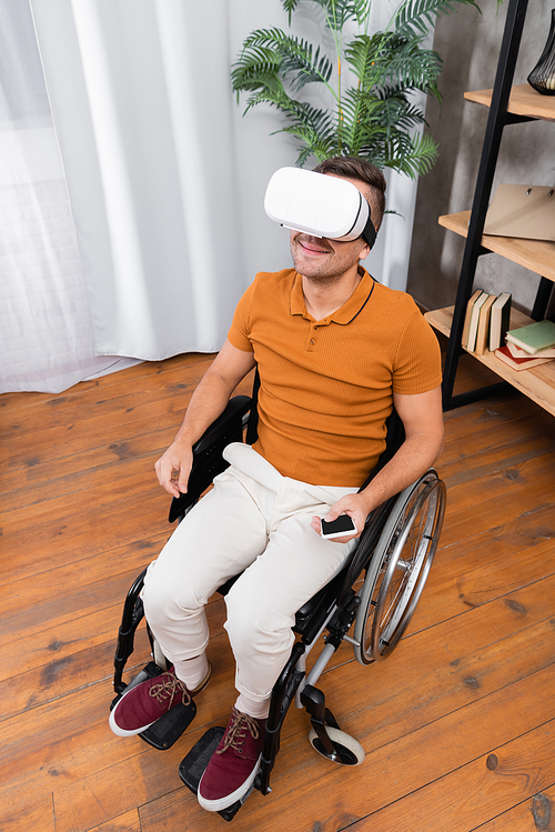 high angle view of disabled man smiling while gaming in vr headset at home