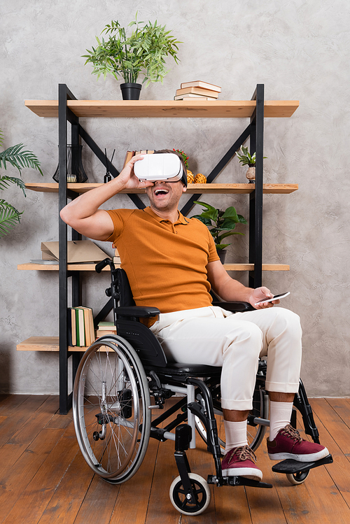 excited man adjusting vr headset while gaming in wheelchair at home