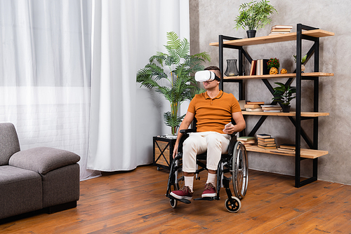young handicapped man holding mobile phone while gaming in vr headset at home