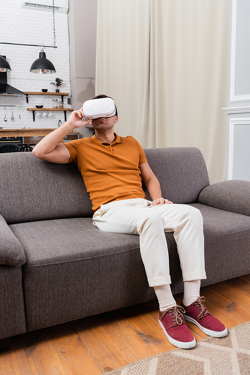 man adjusting vr headset while gaming on couch at home