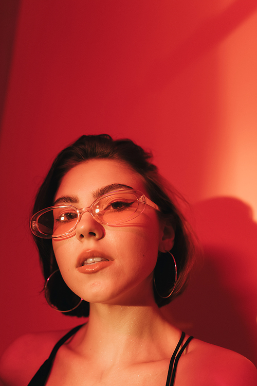 portrait of young woman in sunglasses  on red background