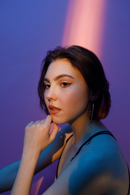 portrait of thoughtful young woman on violet and pink background