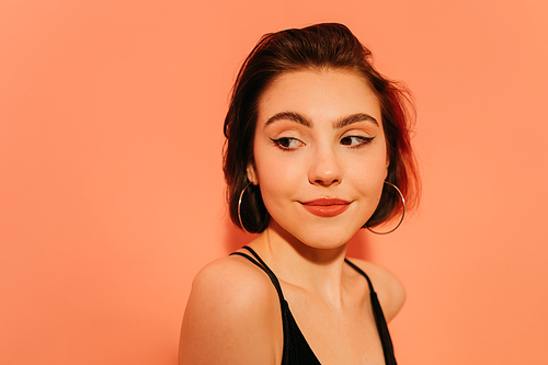 shy young woman with cat eyes makeup on orange background