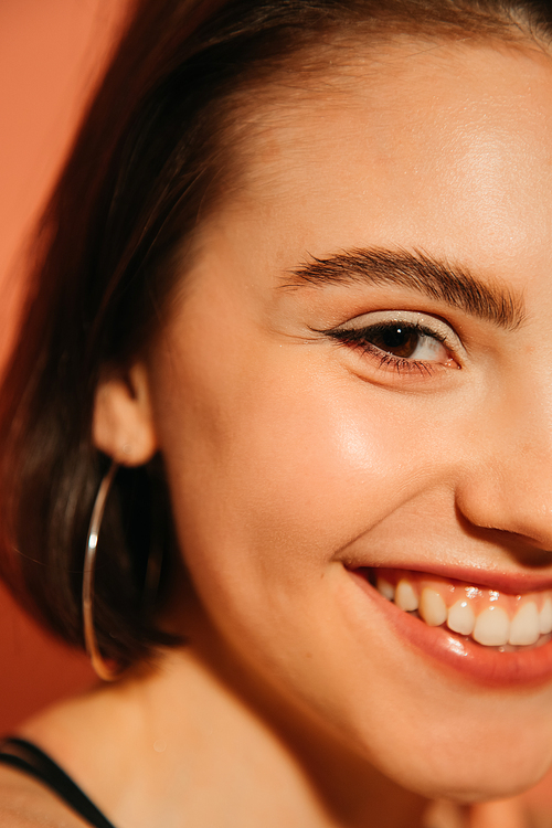 close up of smiling young woman face with summer make up and cat eyes isolated on orange