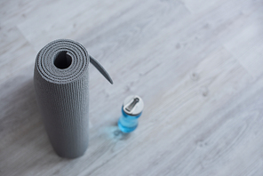 selective of rolled fitness mat near sports bottle with water