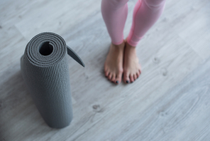 selective focus of yoga mat near barefoot woman, cropped view