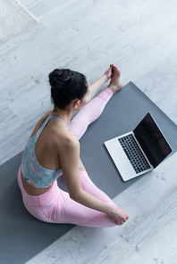 overhead view of brunette woman practicing yoga near laptop with blank screen
