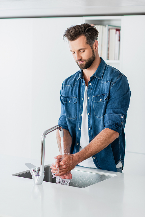 adult man in denim shirt washing hands at home