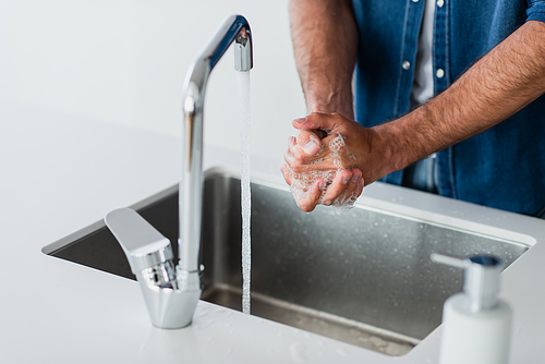 partial view of man washing hands at home on blurred foreground