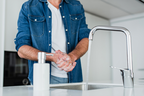 cropped view of man washing hands with soap at home