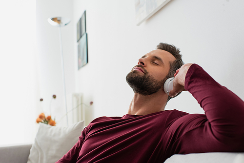 relaxing man listening music in wireless headphones with closed eyes