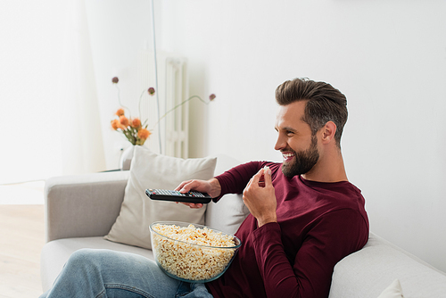 laughing man eating popcorn while watching comedy film in living room