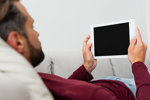 man holding digital tablet with blank screen while resting at home