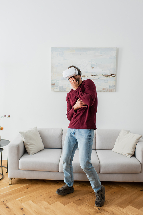 scared man in vr headset covering mouth with hand while gaming at home