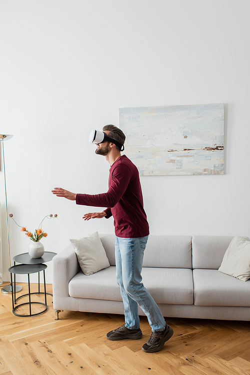 full length view of adult man in vr headset gaming in living room