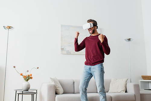 excited man in vr headset shouting while showing triumph gesture