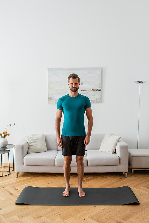 sportive barefoot man  while standing in mountain pose at home
