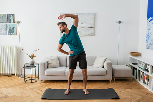 full length view of barefoot man in sportswear practicing yoga at home