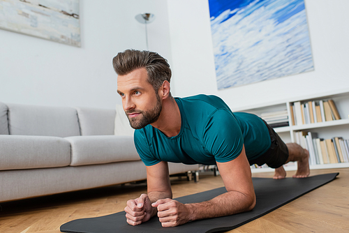 barefoot man practicing yoga in plank pose at home