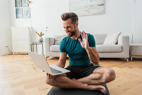happy man having video call on laptop while practicing yoga at home