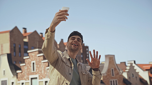 happy man waving hand while having video call on smartphone