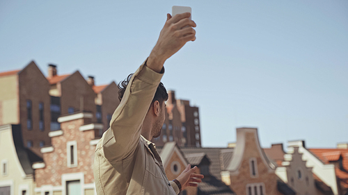 man holding smartphone while taking photo of buildings