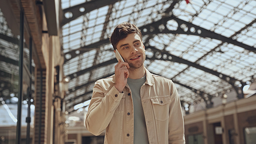 smiling man talking on smartphone in shopping mall