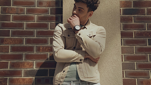 man in beige jacket looking away near building outdoors