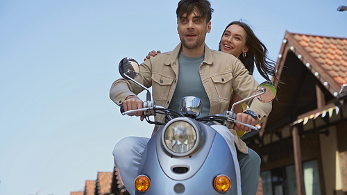 cheerful man and woman riding motorcycle outside