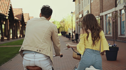 back view of man and woman riding bicycles on street