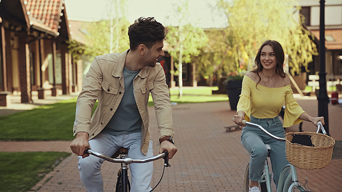 smiling man and woman riding bicycles on street