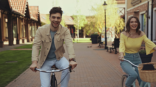 happy man and woman riding bicycles on street