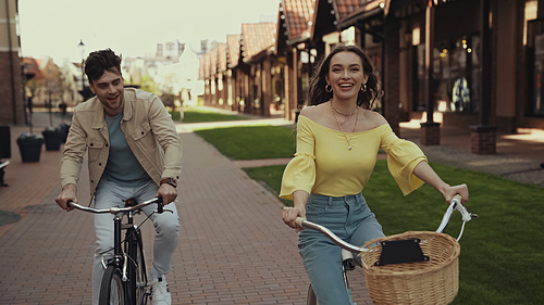 positive woman and man riding bicycles on street
