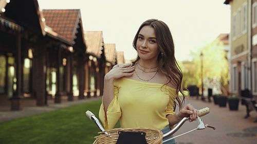 pretty young woman in yellow blouse smiling while riding bicycle outside