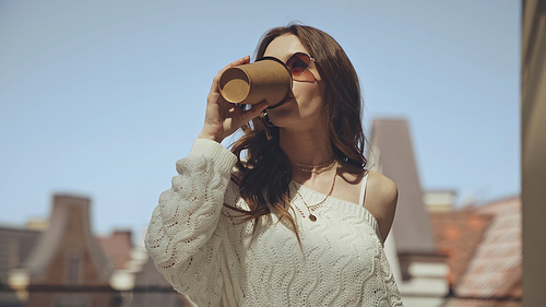 young woman in sunglasses drinking coffee to go outside