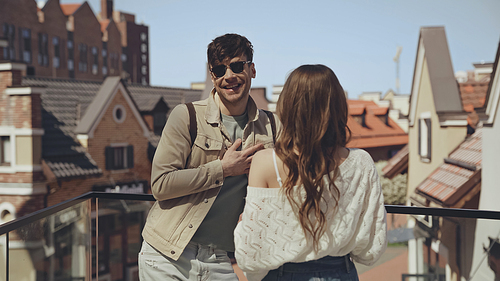 happy man in sunglasses talking with woman outside