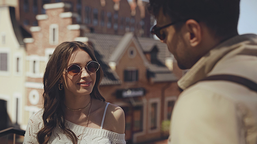 happy woman in sunglasses looking at blurred man