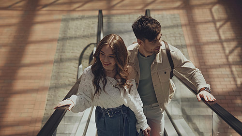 high angle view of happy man and woman on escalator in shopping mall