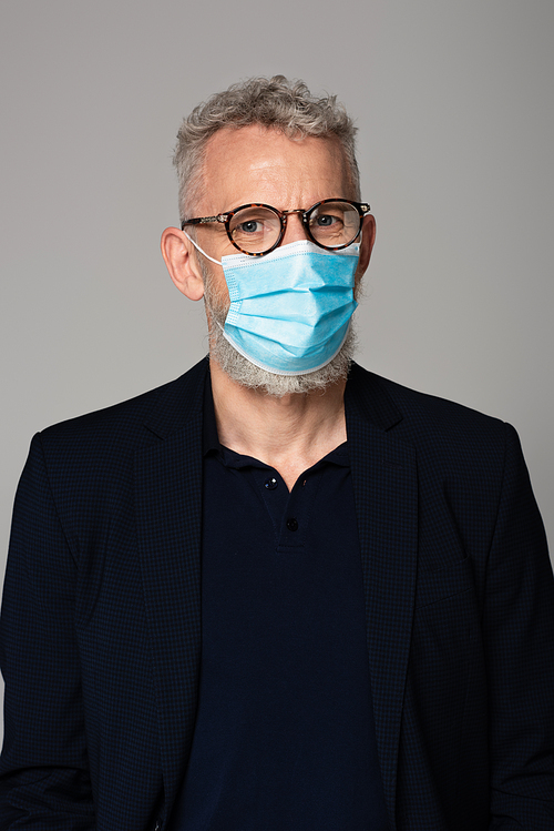 mature man with grey hair in medical mask isolated on grey