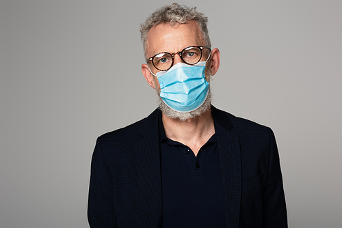 middle aged man with grey hair in glasses and medical mask isolated on grey