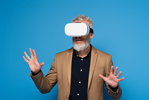 middle aged man in vr headset gesturing isolated on blue