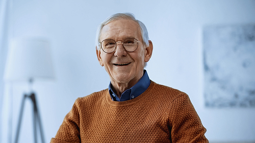 smiling elderly man in glasses  in modern living room